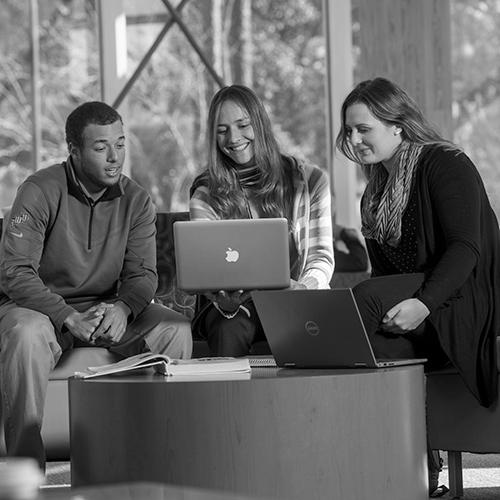 three students studying together in the college of business building atrium